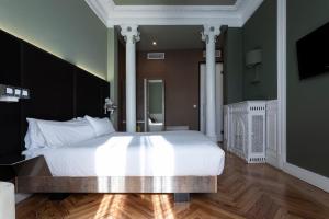 马德里利尔塔德广场小皇宫酒店的卧室配有白色大床和白色枕头