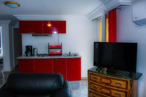 塔巴卡Résidence Les Camélias的一间带红色橱柜的厨房和一台平面电视