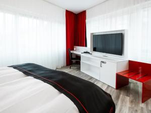 汉诺威DORMERO Hotel Hannover-Langenhagen Airport的一间带电视和床的客厅
