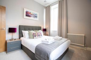 温莎Urban Living's - Windsor Castle Luxury Apartments的一间卧室配有一张大床和两条毛巾