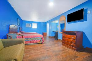 科珀斯克里斯蒂Monterrey Motel Padre Island, Corpus Christi BY OYO的一间带蓝色墙壁、一张床和电视的卧室