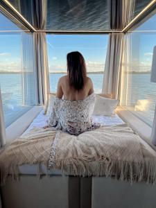 梅尔诺Domki na wodzie - HT Houseboats - with sauna, jacuzzi massage chair的坐在窗前床边的女人