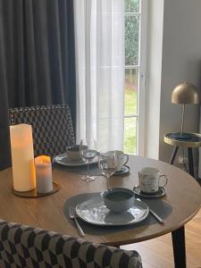 BaliceKraków Green Hill Luxury Apartment的木桌,带盘子和玻璃杯,蜡烛