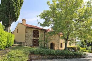 毕威格利亚努Residenza le Colline del Paradiso的一座古老的石头房子,有树和灌木