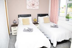 斯坦维尔7SM Dreams Unlimited Serviced Accommodation- Stanwell-Staines-Heathrow的卧室内的两张床,配有白色床单