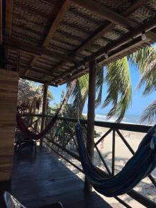 圣玛尔塔HOSTAL Estrellas del tayrona playa的一个带吊床的门廊和海滩
