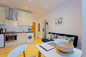 伦敦Calabria 2 - Cosy apartment的厨房以及带桌椅的起居室。