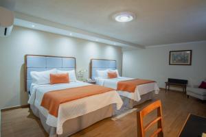 马特瓦拉Hotel del Parque的一间卧室配有两张带橙色和白色床单的床