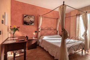 Petrignano巴巴罗萨B&B别墅酒店的一间卧室配有一张天蓬床、一张桌子和一张书桌。