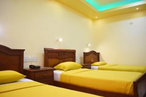 瓜亚基尔Hostal Galápagos - Guayaquil的一间设有三张黄色床单的房间