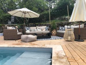 Les AssionsIdyllic Roulotte的带沙发和遮阳伞的天井以及游泳池。
