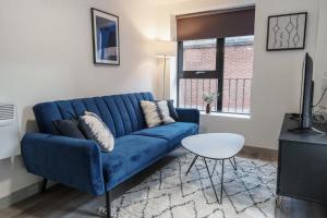 利物浦Lovely 1 Bed Apartment in Liverpool Centre的客厅配有一张蓝色的沙发,配有一张桌子