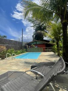 坎布里Aldeia de Camburi的棕榈树游泳池旁的椅子