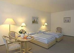 奥尔登堡Stadthotel Oldenburg的酒店客房带两张床和一张桌子以及椅子。