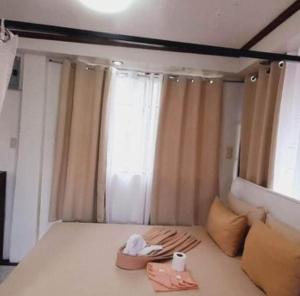 碧瑶De Hagan Transient Baguio City的一间卧室配有床,窗户配有2条毛巾
