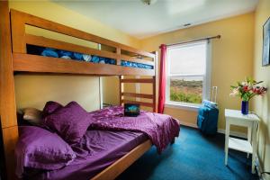 佩斯卡德罗HI鸽点灯塔旅舍的一间卧室配有一张带紫色床单的双层床和一扇窗户。