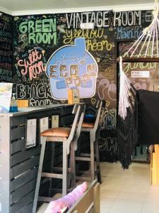 麦德林Casa Egos Pop Laureles的一间酒吧,里面设有两个凳子和涂有涂鸦的墙壁
