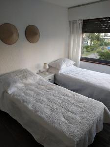 埃斯特角城Frente a playa brava的配有窗户的酒店客房内的两张床