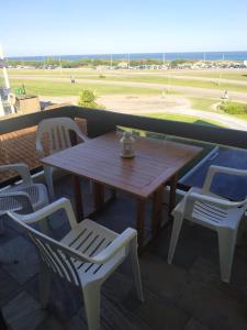 埃斯特角城Frente a playa brava的阳台配有一张木桌和椅子,享有田野美景