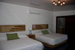戈尔菲托Hotel Samoa del Sur的卧室内的两张床,配有白色床单和绿色枕头