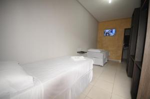 因佩拉特里斯La Bella Hotel的一间卧室设有两张床,墙上配有电视。