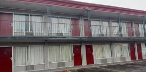 沃思堡Red Roof Inn Fort Worth West的一座建筑,设有红色的门和阳台