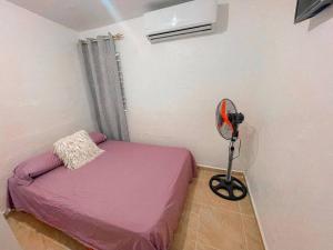 Villa IsabelaAcogedora casa de 2 habitaciones的一间小卧室,配有粉红色的床和风扇