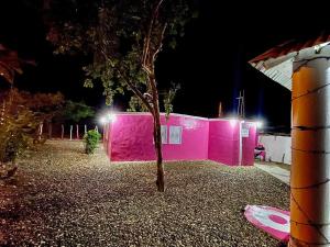 Villa IsabelaAcogedora casa de 2 habitaciones的前面有棵树的粉红色建筑