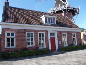 温斯霍滕Zeer sfeervol gastenverblijf in Het Molenhuisje met woonkamer en keuken的红砖建筑,顶部有风车