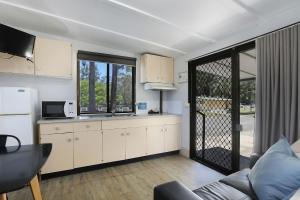 科夫斯港Reflections Coffs Harbour - Holiday Park的厨房配有沙发、冰箱和桌子