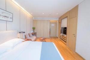 苏州红璞礼遇酒店的一间带白色床的卧室和一间客厅
