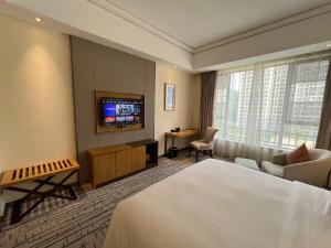 广州广州南鸿澳斯特酒店的酒店客房,配有床和电视