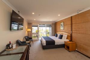 美洲河袋鼠岛美居酒店的一间卧室配有一张床、一张书桌和一台电视。