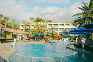 西归浦市Hotel Toscana的度假村内的大型游泳池,配有蓝色遮阳伞
