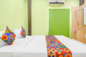 海得拉巴FabExpress Airport Stay Inn的卧室配有白色的床和色彩缤纷的枕头
