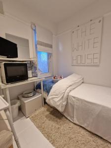 沃尔瑟姆克罗斯The White House的一间白色卧室,配有床和电视