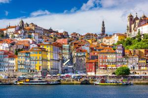 波尔图Oca Ribeira do Porto AT的水面上拥有多彩建筑和船只的城市
