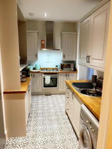 普里茅斯TWO BEDROOM Private development & concierge的厨房配有白色橱柜和瓷砖地板。