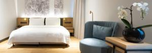 EžeraičiaiVilnius Grand Resort的卧室配有白色的床和蓝色椅子