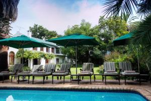 阿多伍德尔乡间别墅及spa酒店的一组椅子和遮阳伞,位于游泳池旁