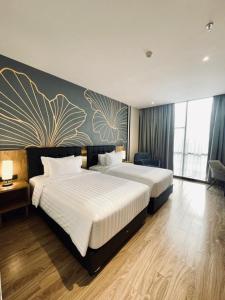 棉兰Grand Central Premier的酒店客房设有两张床,墙上挂有绘画作品