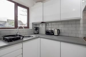 达格纳姆Lovely House in Dagenham / Barking with free parking, WiFi & Garden的厨房配有白色橱柜、水槽和窗户。