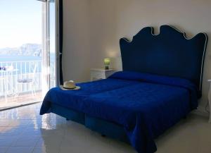 波西塔诺Casa Marrapese的一间卧室配有一张蓝色的床,上面有帽子