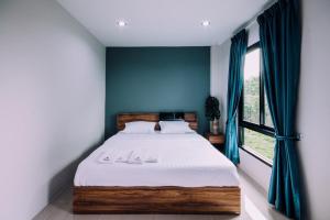 邦波The Living Hotel SamutPrakan的一间卧室配有一张蓝色墙壁的床和一扇窗户
