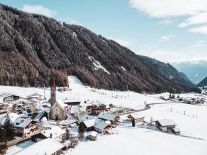 瓦勒斯Familienhotel Huber的被雪覆盖的村庄,背景是山