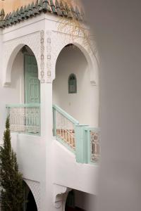 马拉喀什Marrakech Riads, Angsana Heritage Collection的白色的建筑,设有绿门和阳台