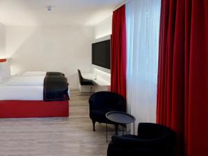 达姆施塔特DORMERO Hotel Darmstadt的酒店客房配有一张床、一张书桌和红色窗帘