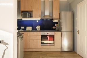 朴次茅斯Blue Sparrow House - parking的厨房配有木制橱柜和不锈钢冰箱。