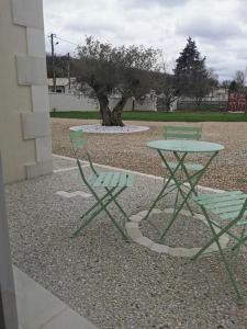 尚尼耶Angoulême Nord location Chambre indépendante的两把绿色椅子和一张桌子,一棵树