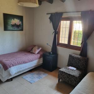 卢汉德库约El descanso, zona de bodegas的卧室配有床、椅子和窗户。